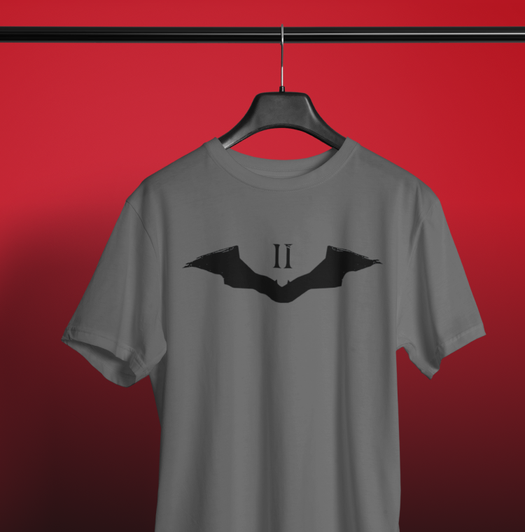 A gray short-sleeve t-shirt hanging on a black hanger against a red gradient background. The shirt features a black bat-wing graphic with the Roman numeral 'II' printed in the center.